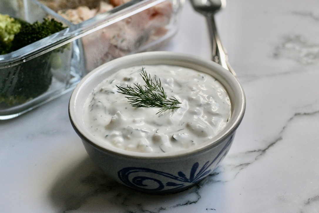 a small white bowl of feta and yogurt dip on a white counter top
