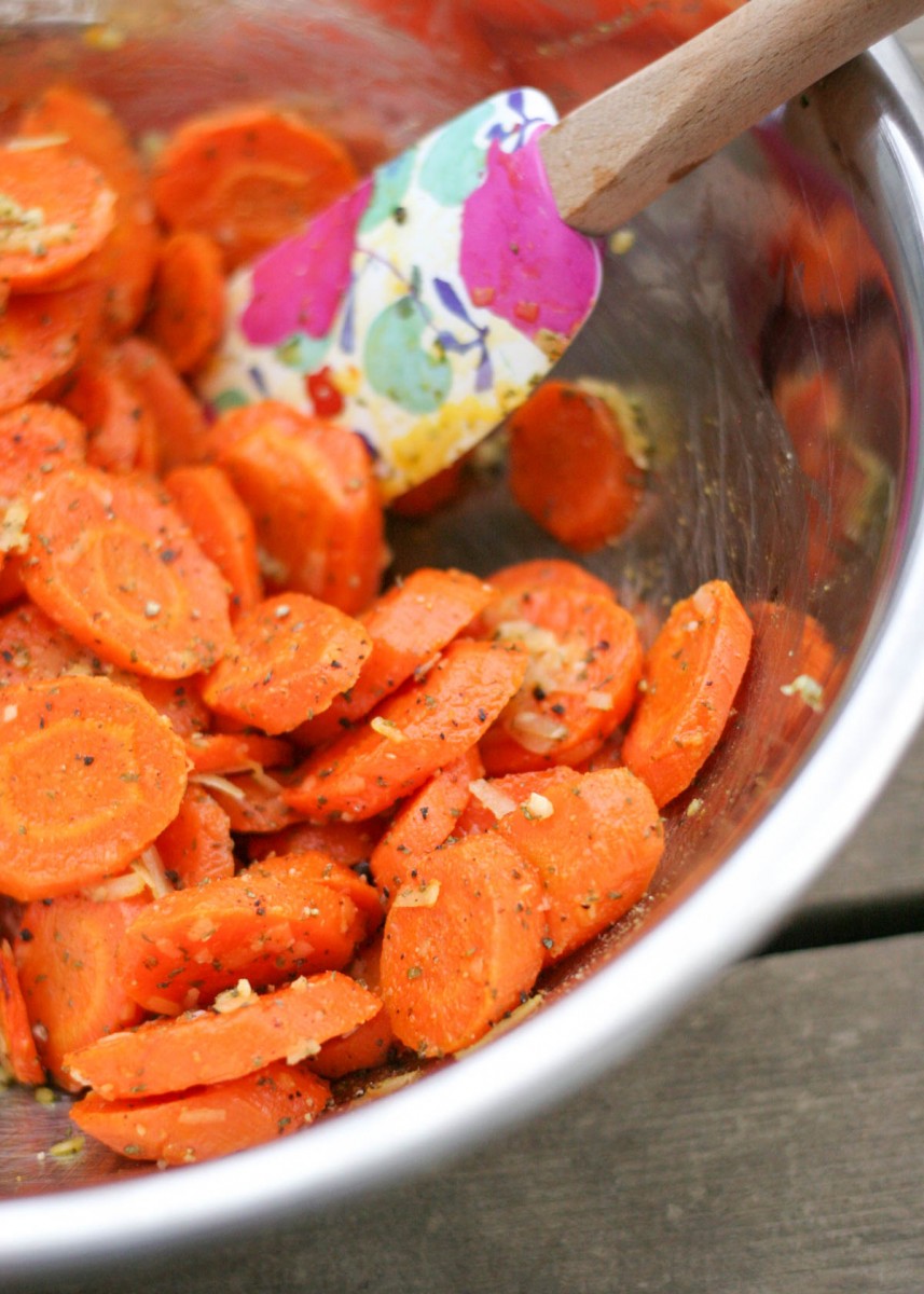 Easy Roasted Garlic Carrots with Parmesan Cheese getting tossed in a large stainless steel bowl