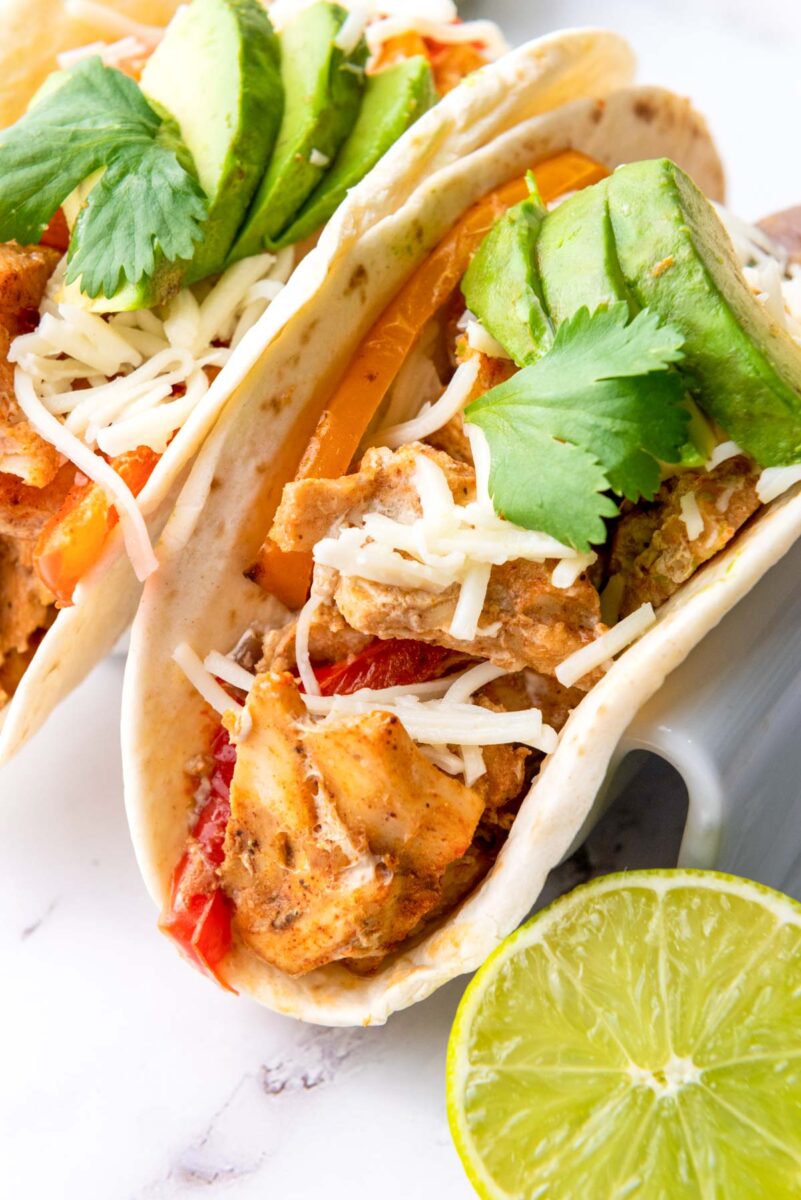 A Chicken Fajita with cilantro and lime on the side.