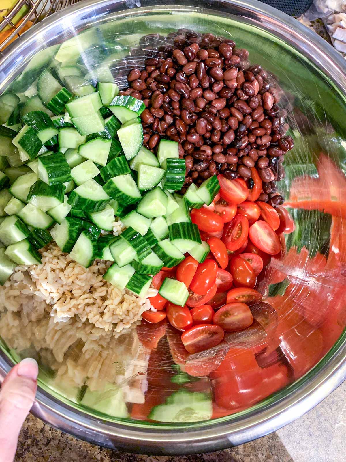 A bowl of black beans, brown rice, tomatoes and cucumber
