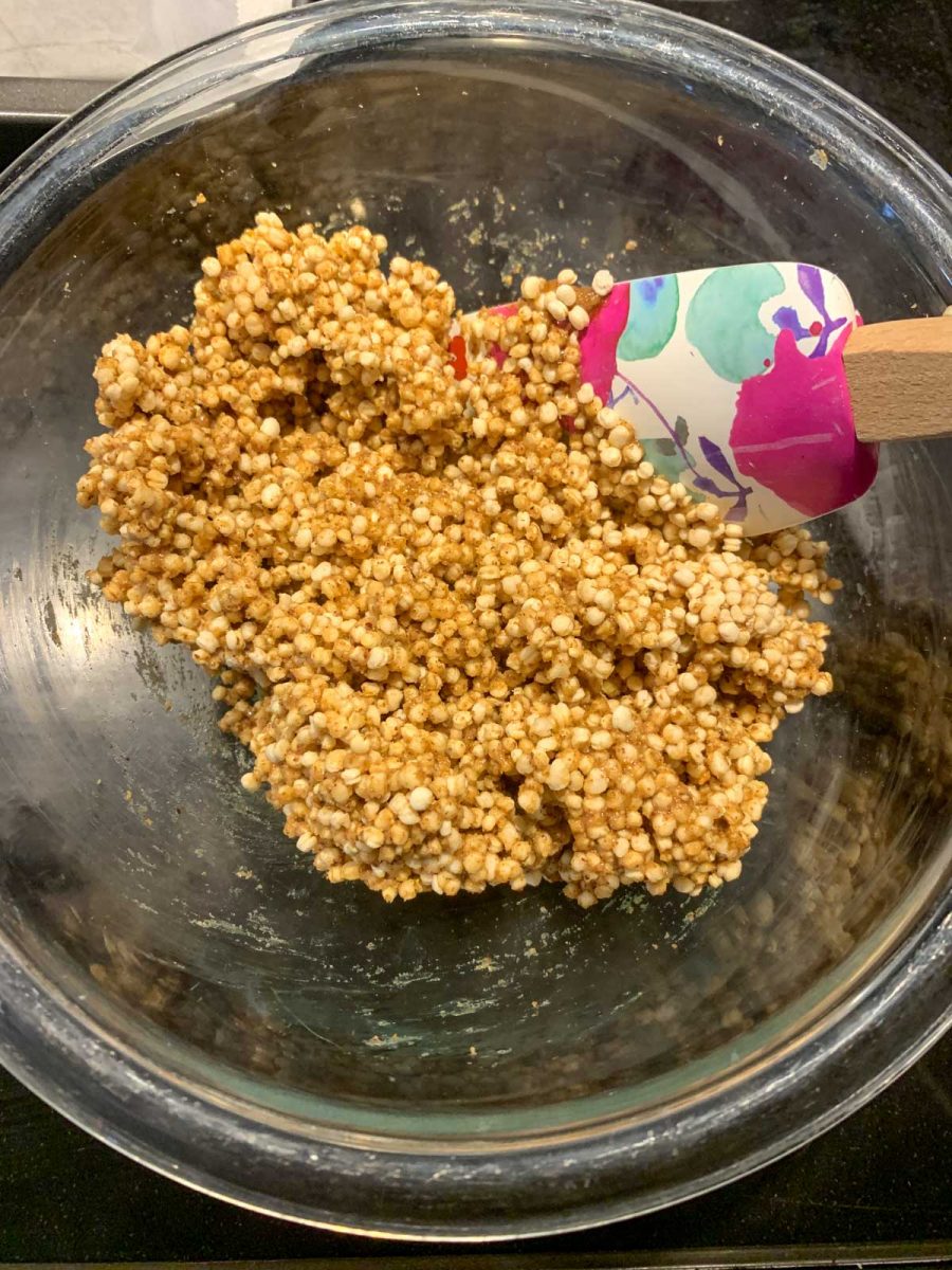 A clear bowl filled with puffed quinoa and honey and almond butter mixture