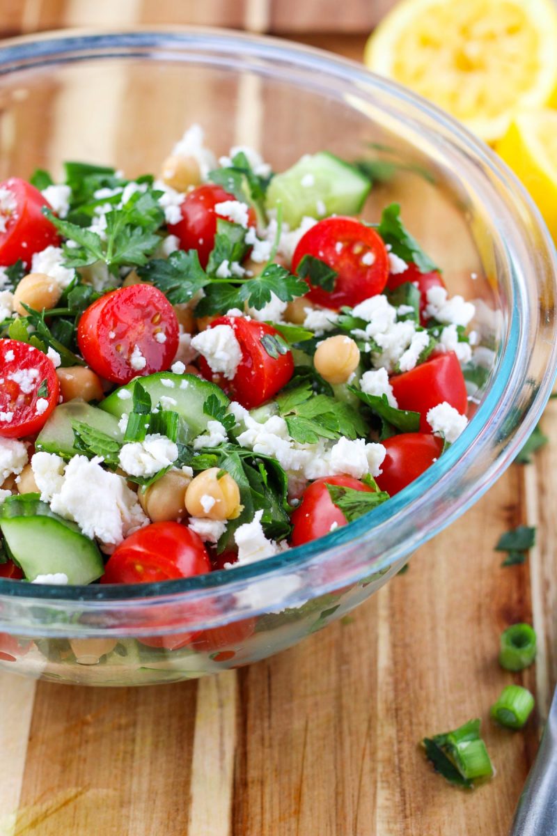 A clear glass bowl filled with Fresh Herb Salad with Chickpeas and Feta