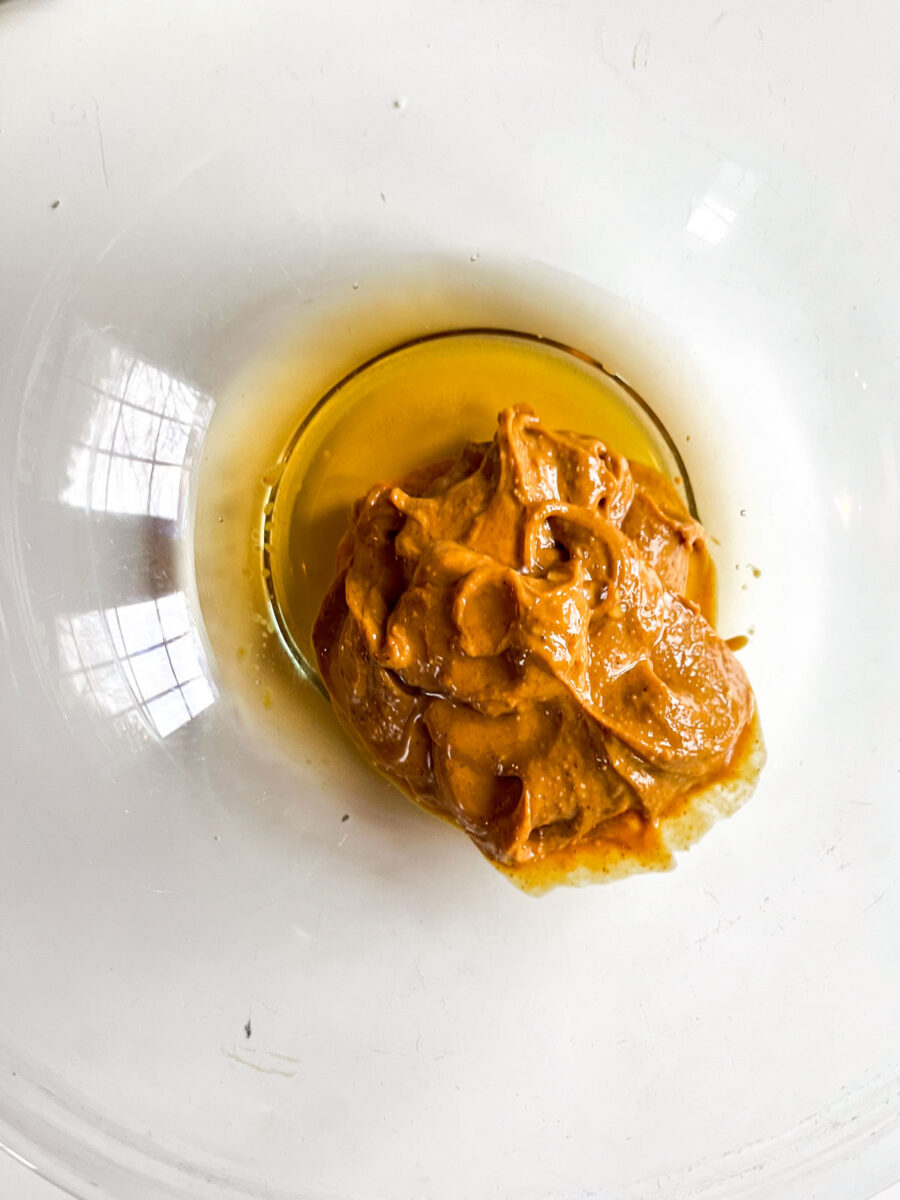 A glass bowl with peanut butter and maple syrup.