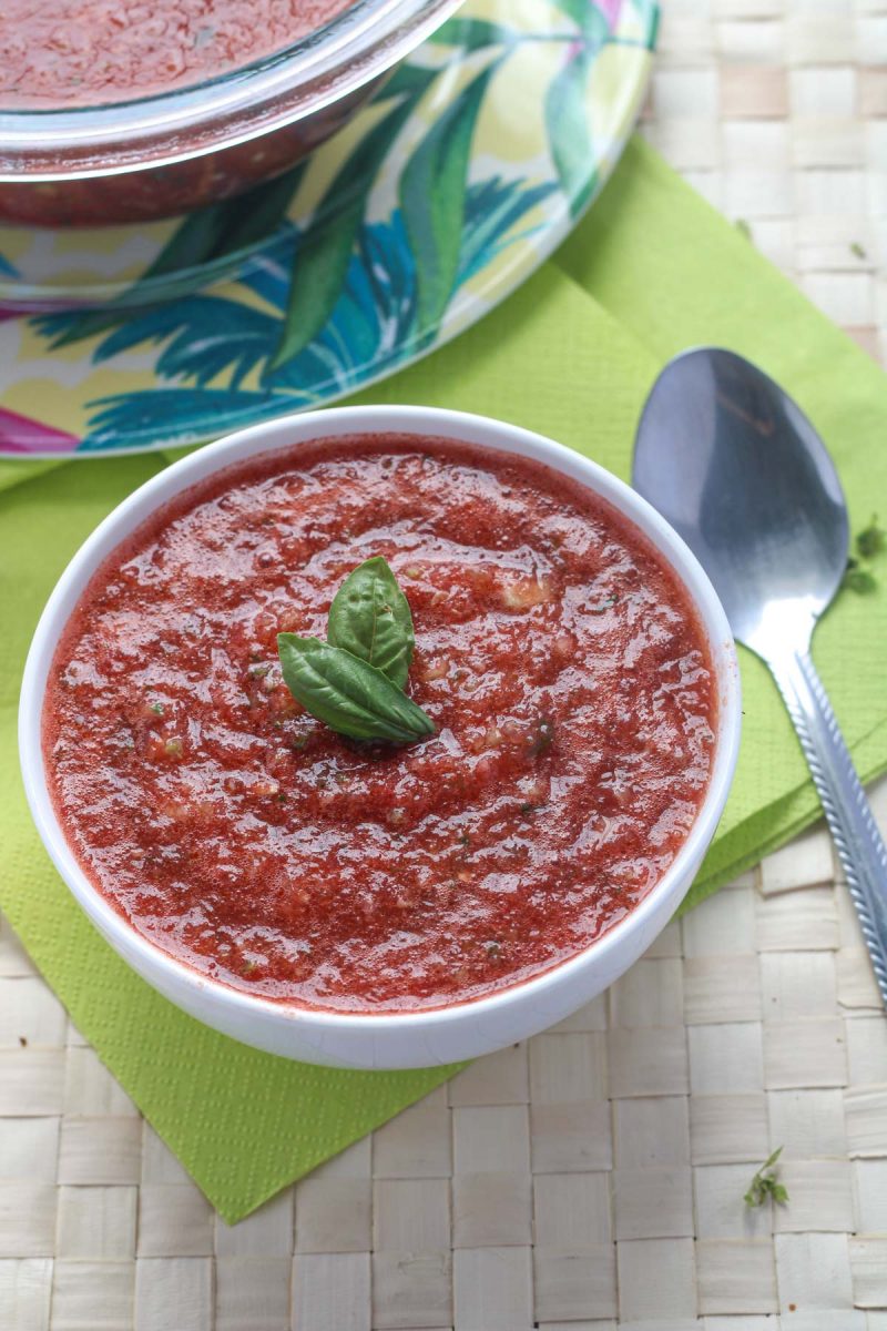 A small white bowl of Easy Watermelon Summer Gazpacho with a silver spoon beside