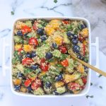 A white dish of Summer Quinoa Salad with Mango and Blueberries with a gold spoon in it