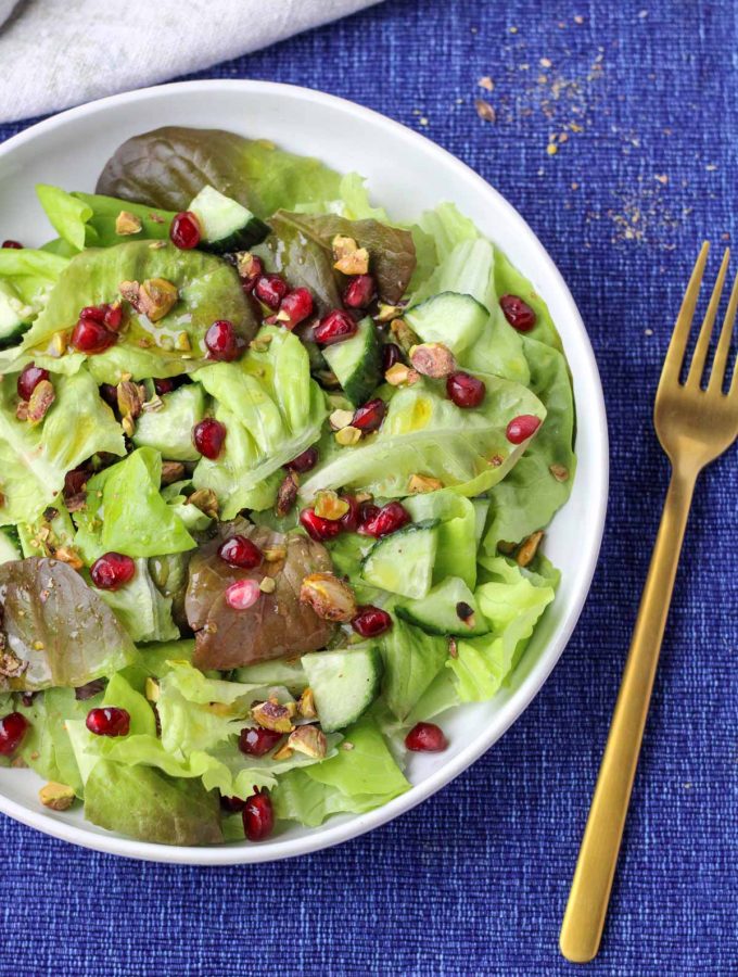 A white plate filled Butter Lettuce and Pomegranate Salad