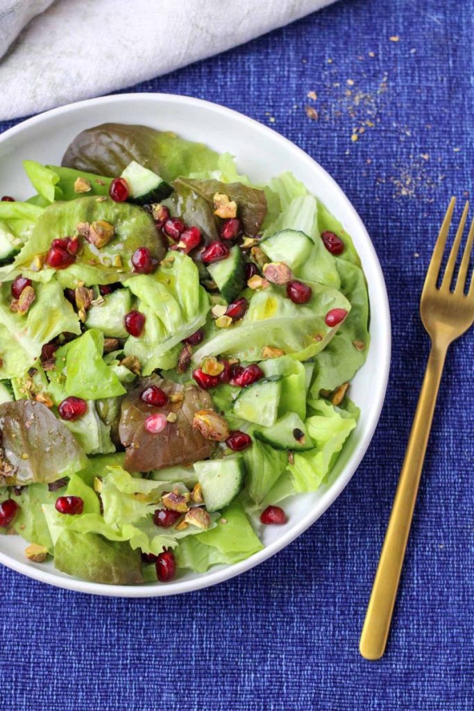 A white plate filled Butter Lettuce and Pomegranate Salad