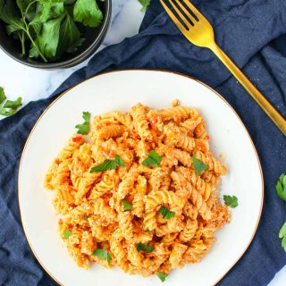 A white plate filled with baked Feta and Cherry Tomato Pasta