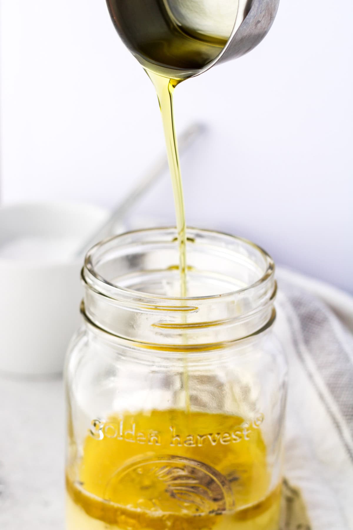 Adding olive oil to a mason jar for a Greek yogurt sauce.