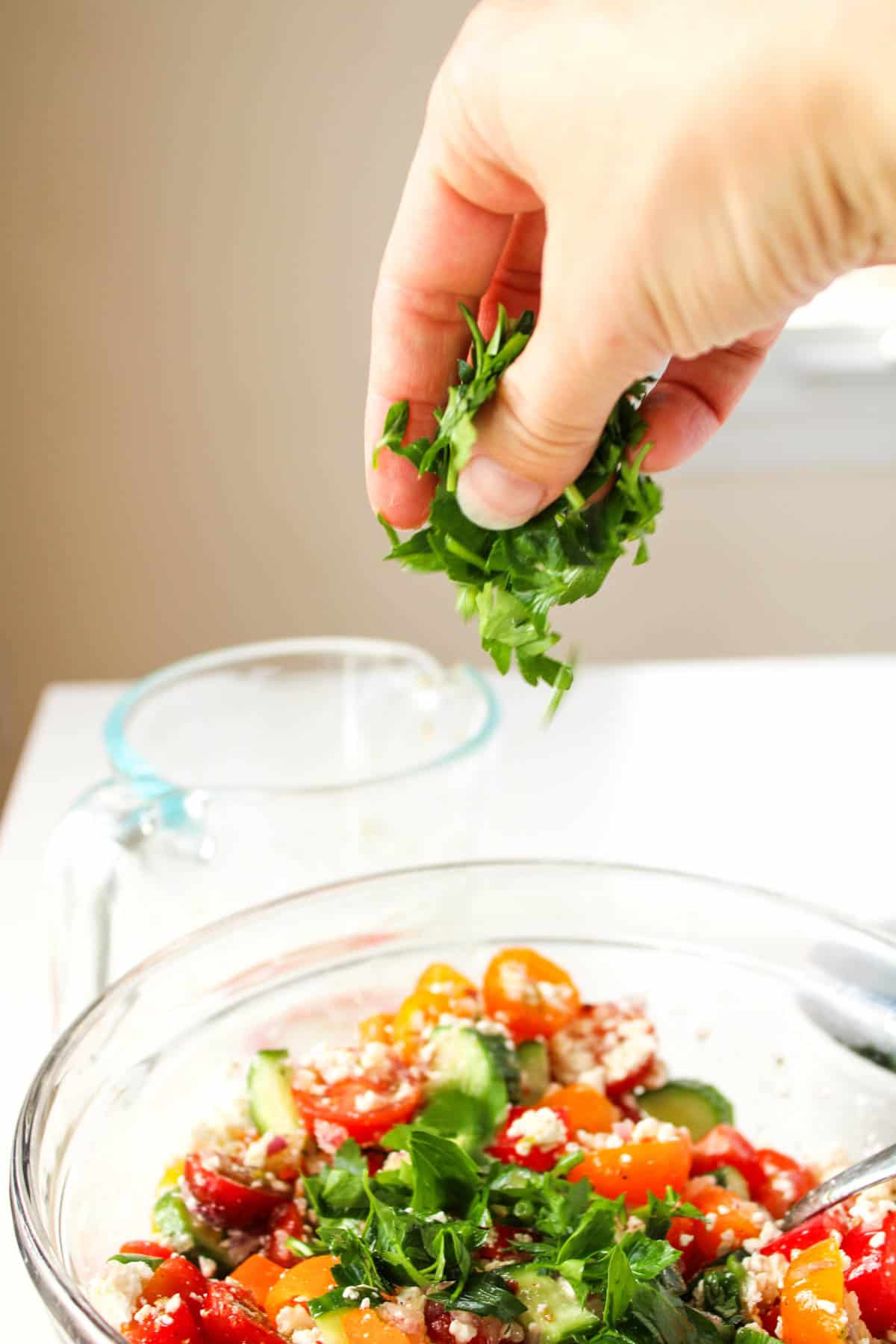 Adding parsley to chopped Greek salad.