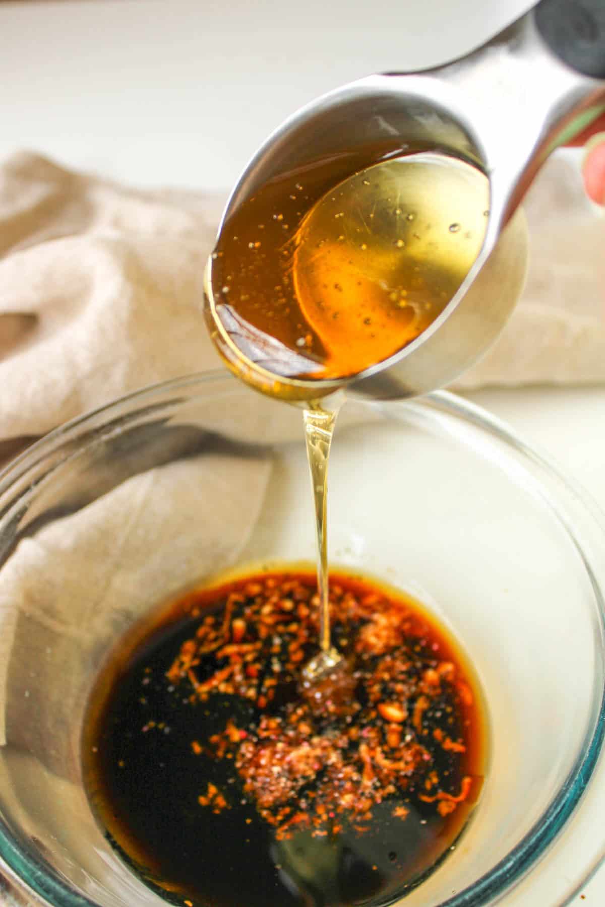 Adding liquid honey to a bowl of soy sauce marinade.