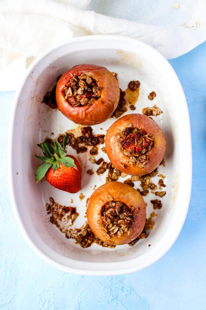 Three baked apples in a white baking dish