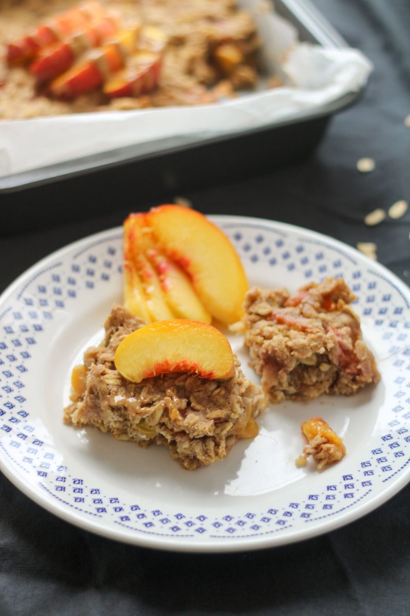 Baked oatmeal with peaches on a white plate with a black table cloth