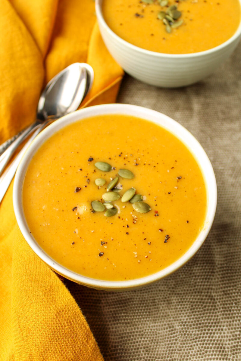 A bowl of roasted butternut squash soup on a grey placemat.