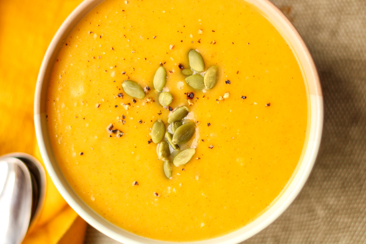 A bowl of roasted butternut squash soup on a grey placemat.