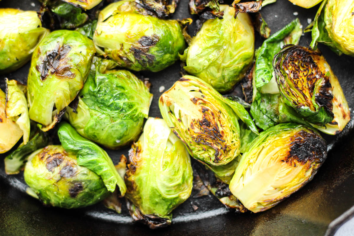 Cut brussel sprouts roasted in a cast iron pan.