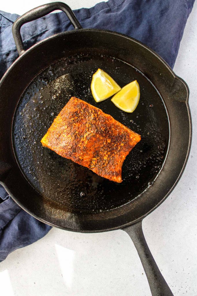 A piece of cooked cajun salmon in a cast iron pan.