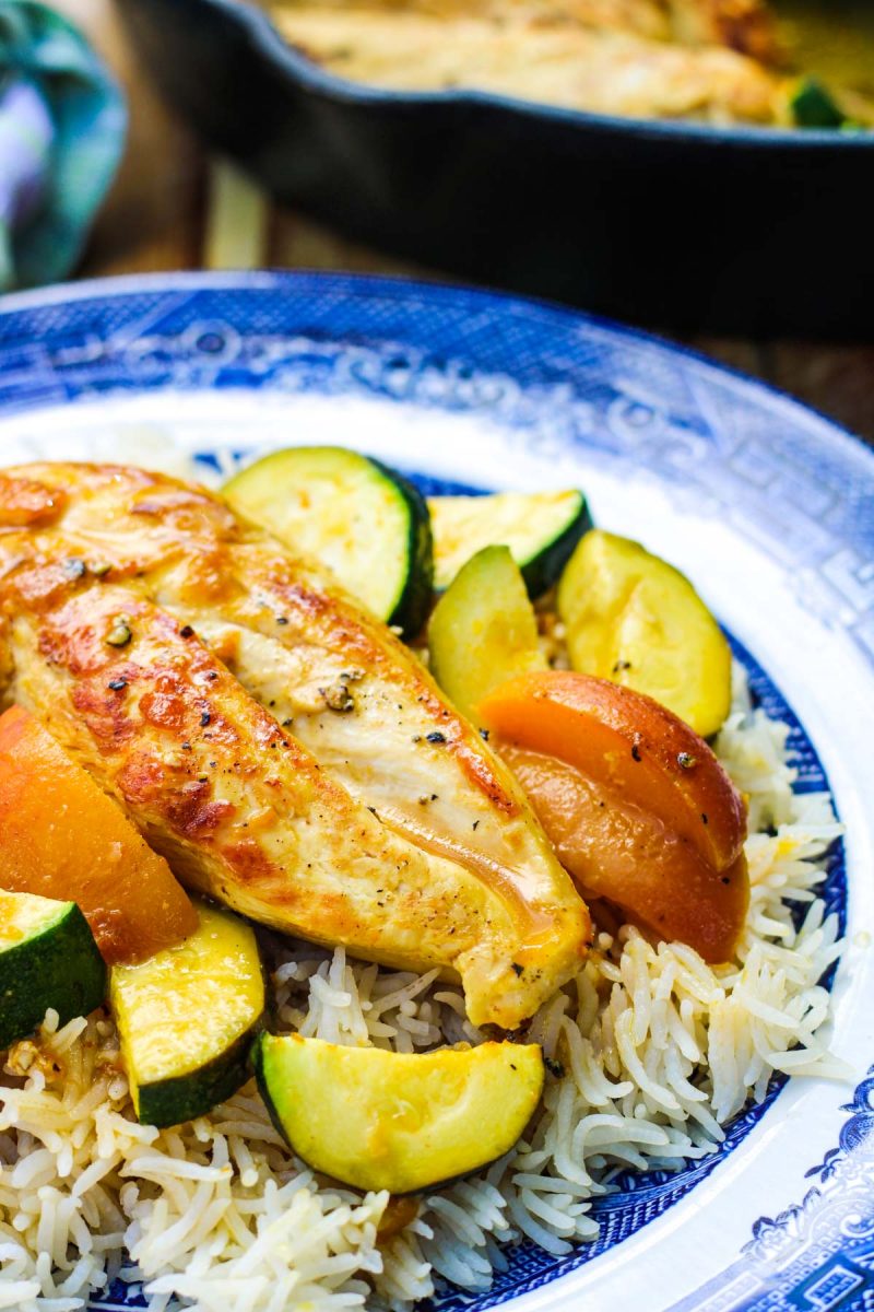 Chicken Breast with Zucchini and Peaches with rice on a blue and white plate