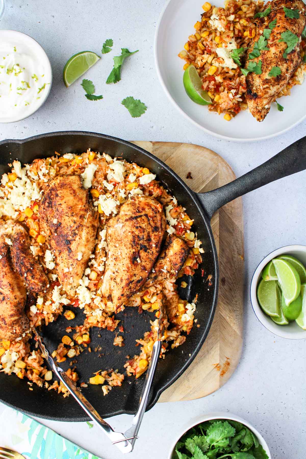 A cast iron pan filled with chicken breasts and rice.