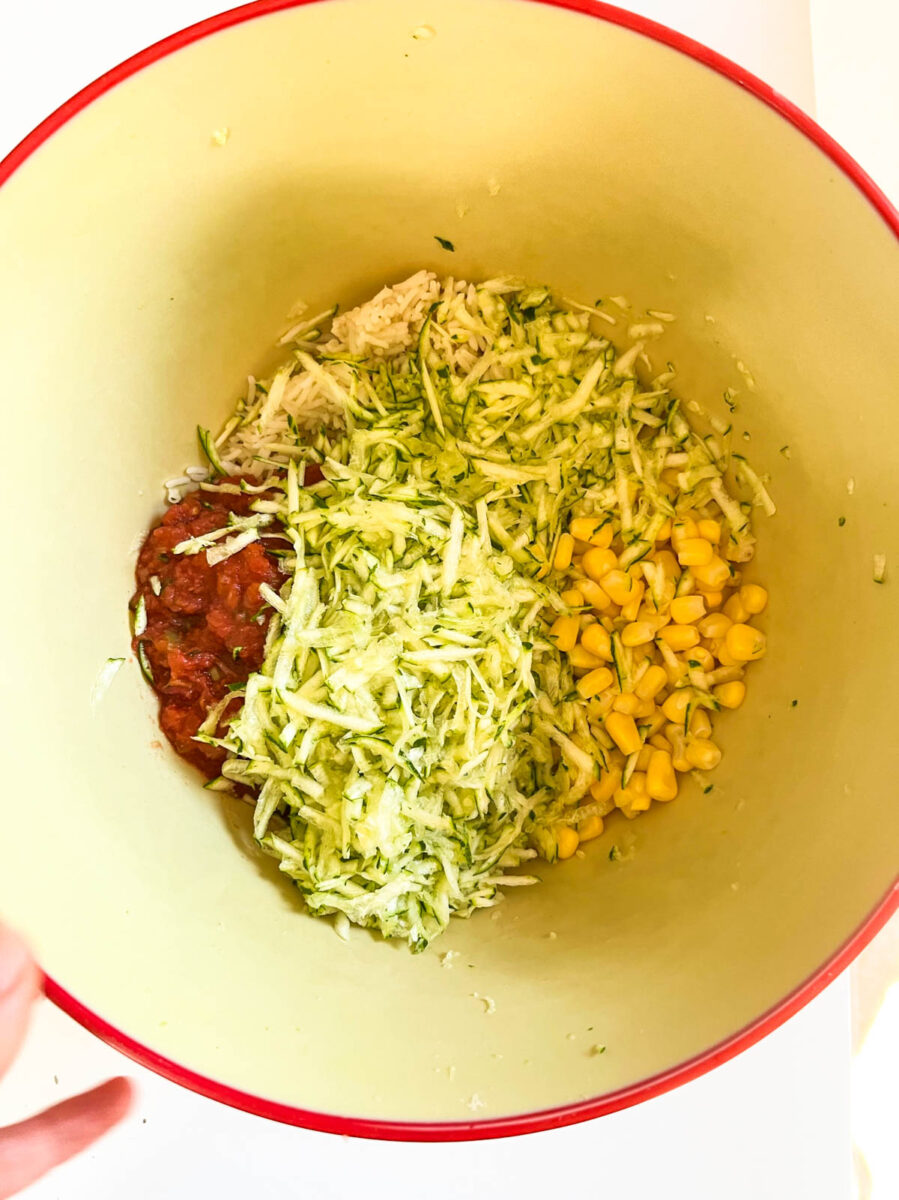 A mixing bowl with zucchini, rice, corn and salsa.