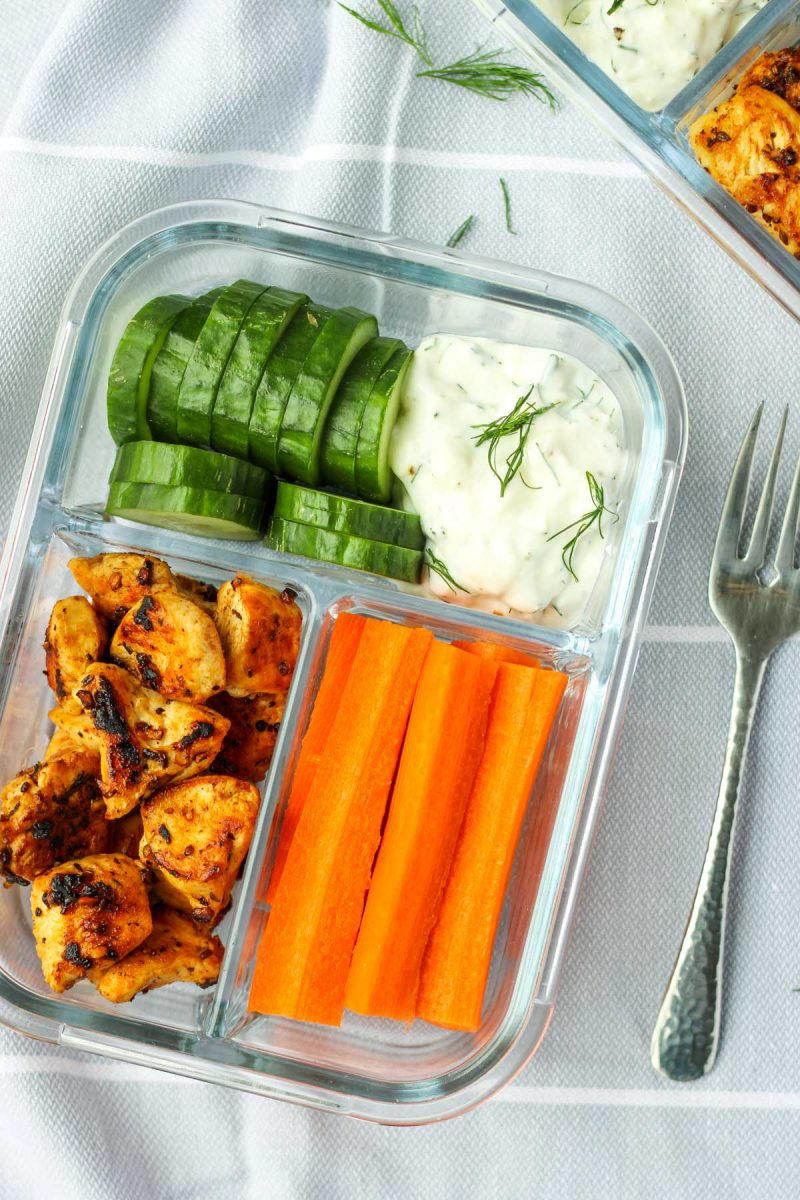 Chicken and veggies with a greek dip in a glass container