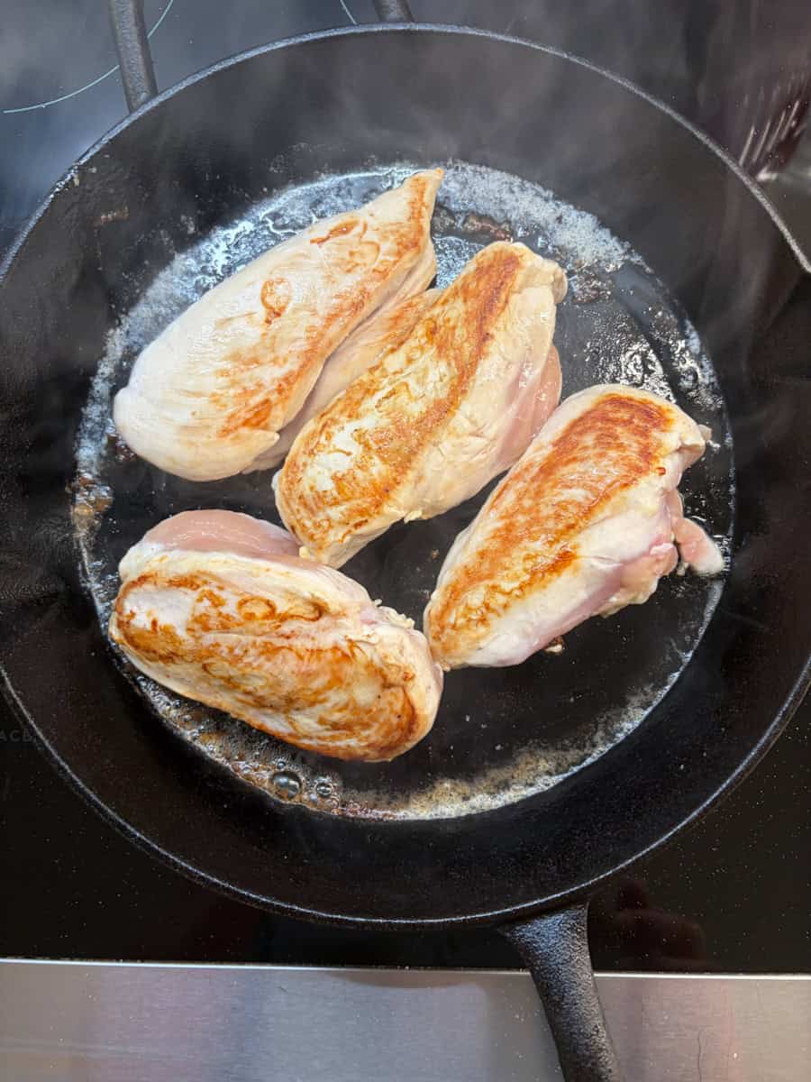 Chicken breasts in a cast iron skillet.