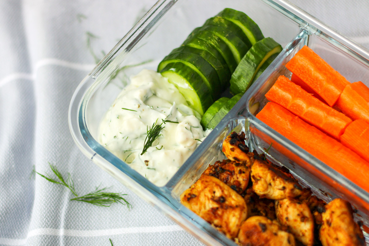 Chicken, cucumbers and carrots with a greek dip in a glasss divided dish