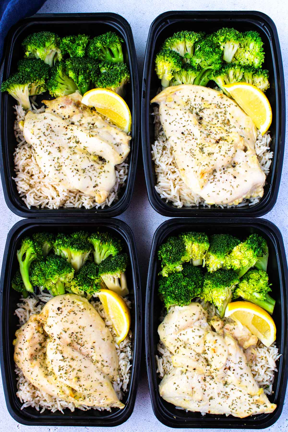 Four meal prep containers with chicken, rice and broccoli meal prep.