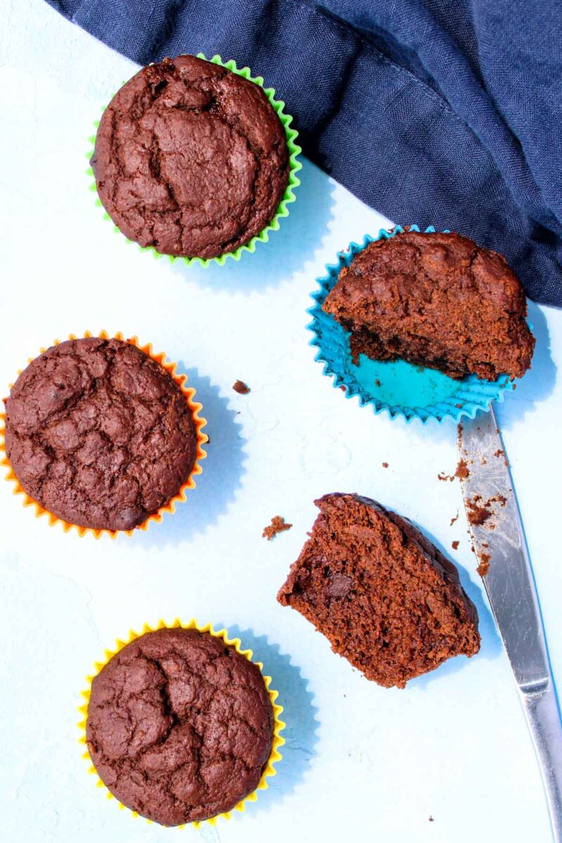 Five chocolate muffins on a white countertop.