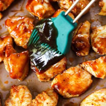 Coating chicken breast chunks with BBQ sauce.