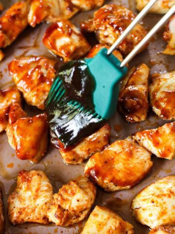 Coating chicken breast chunks with BBQ sauce.