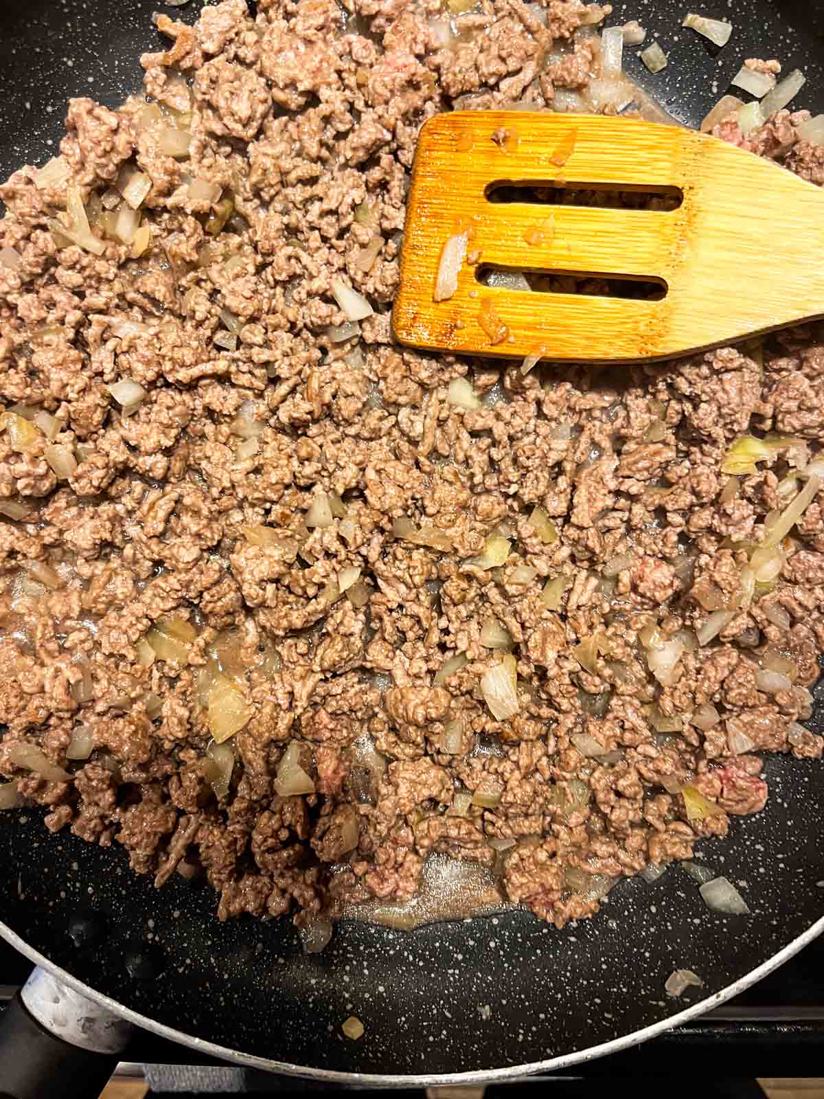 Cooked ground beef with onion in a pan.