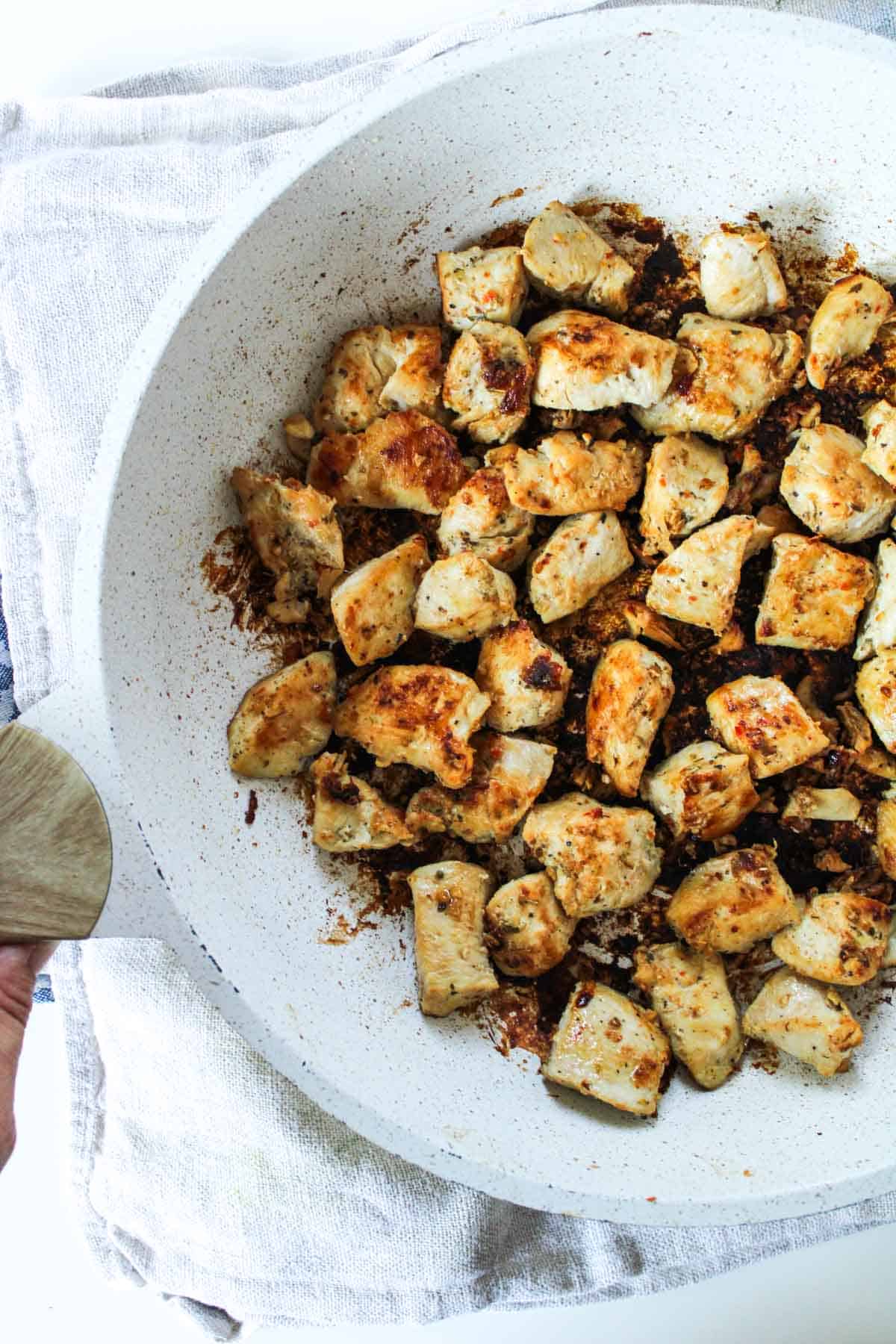 Cooked chicken breast pieces in a white pan.