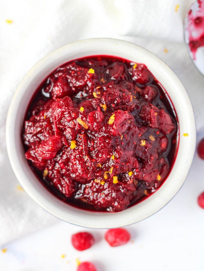 a small white bowl of Cranberry Pomegranate Sauce for the holidays