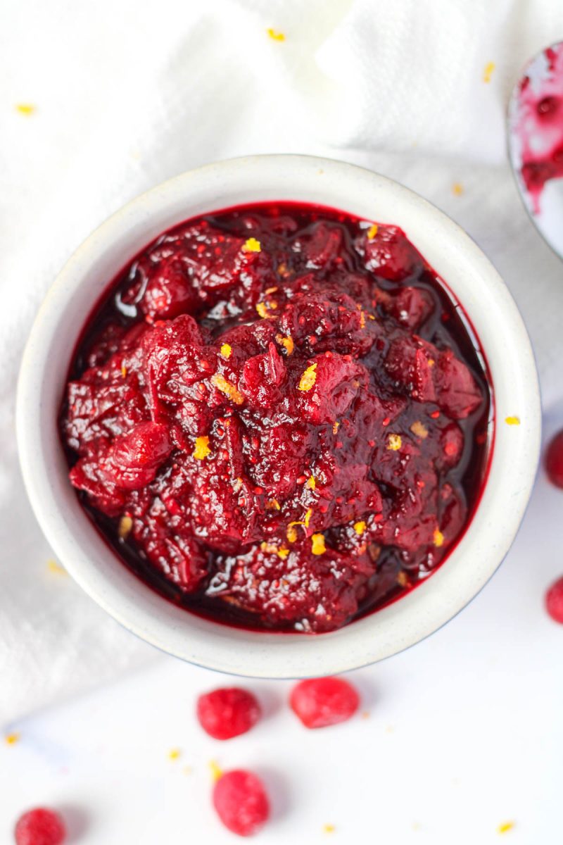 a small white bowl of Cranberry Pomegranate Sauce for the holidays