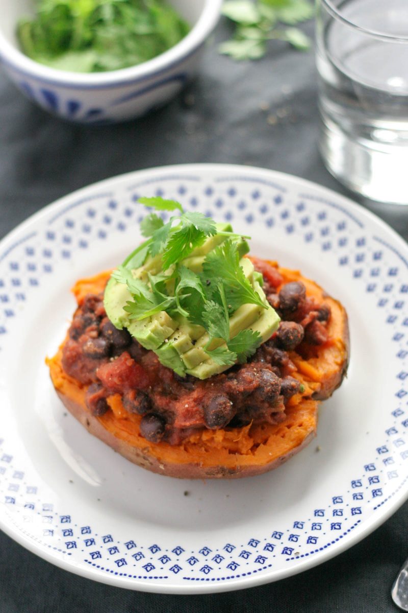 Easy Black Bean Stuffed Sweet Potatoes with Avocado on a white and blue plate