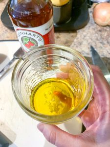 a small mason jar with oil, apple cider vinegar and garlic