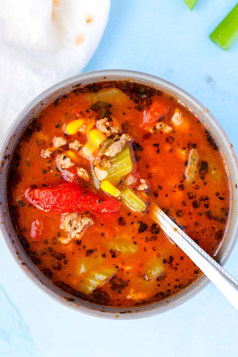 Ground turkey soup with tomatoes and vegetables in a small bowl.