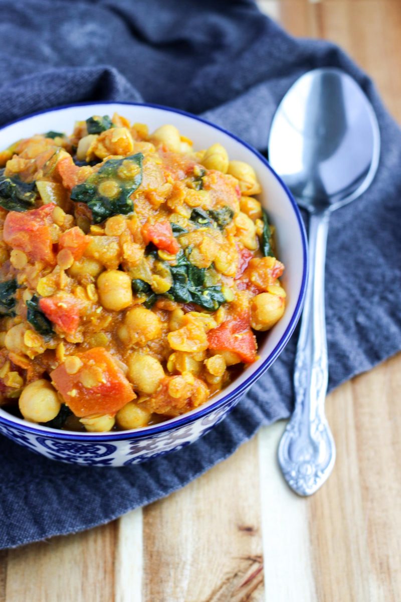 A blue and white bowl filled with chickpea curry on a grey napkin
