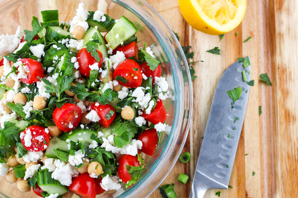 Fresh Herb Salad with Chickpeas and Feta on a wood cutting board with a knife beside