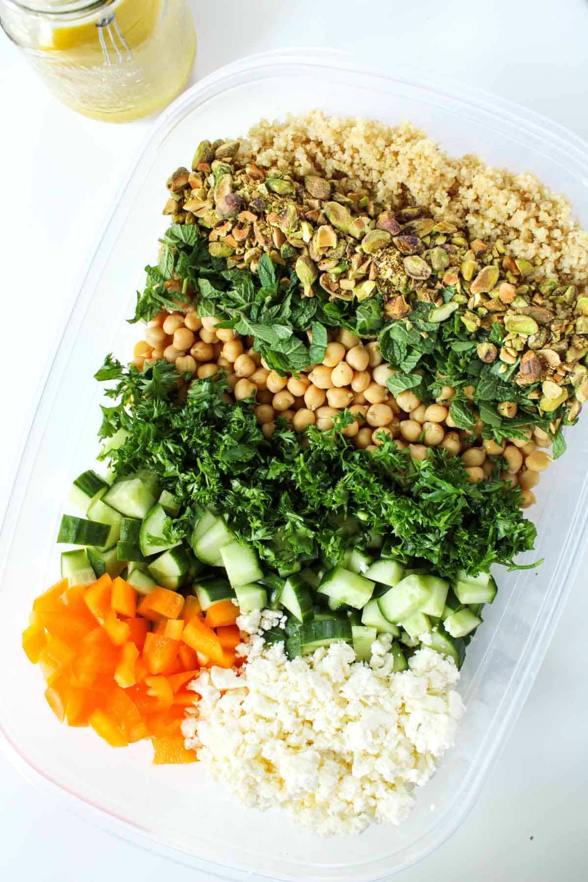 Healthy quinoa salad ingredients in a clear container.