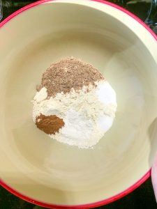 A mixing bowl filled with flour, ground flaxseed, cinnamon, salt, baking soda and xanthan gum