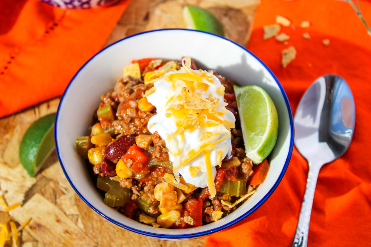 Gluten Free Slow Cooker Chili topped with sour cream with a silver spoon beside