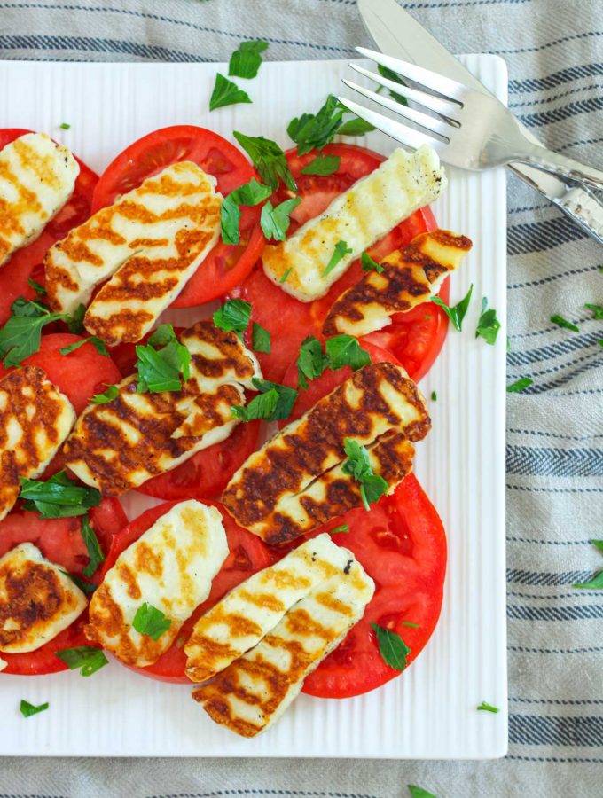 Grilled Halloumi Salad with Tomato and Parsley on a white plate with silver cutlery
