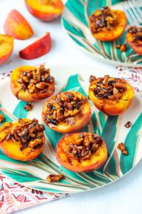 Grilled Peaches with Walnuts on a plate with tropical leaves