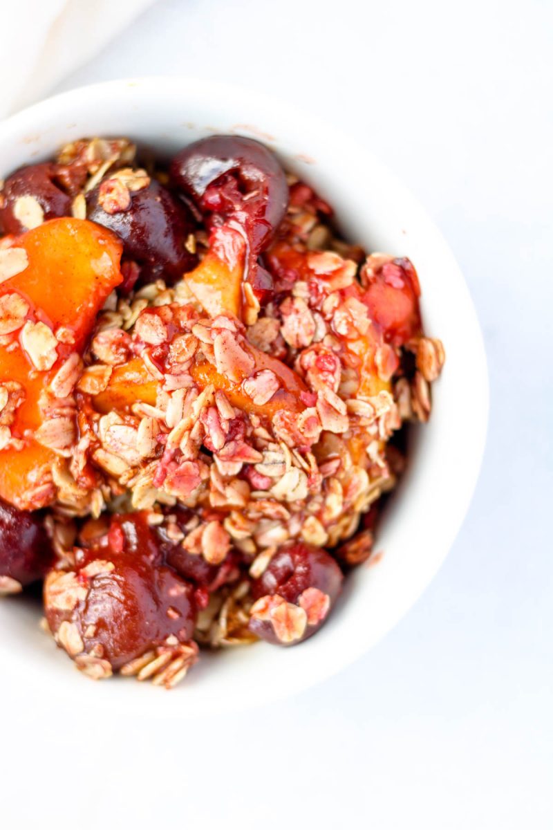 Healthy Cherry and Peach Crisp with Oat Crumble in a small white bowl.