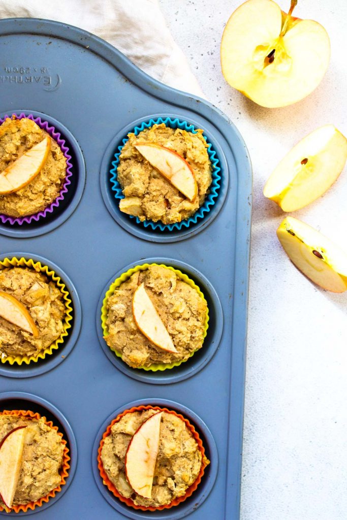 A muffin tin filled with small apple muffins.