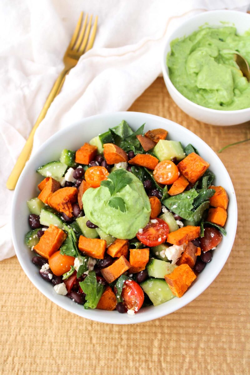 Salad with roasted sweet potatoes, spinach and feta in a white bowl.