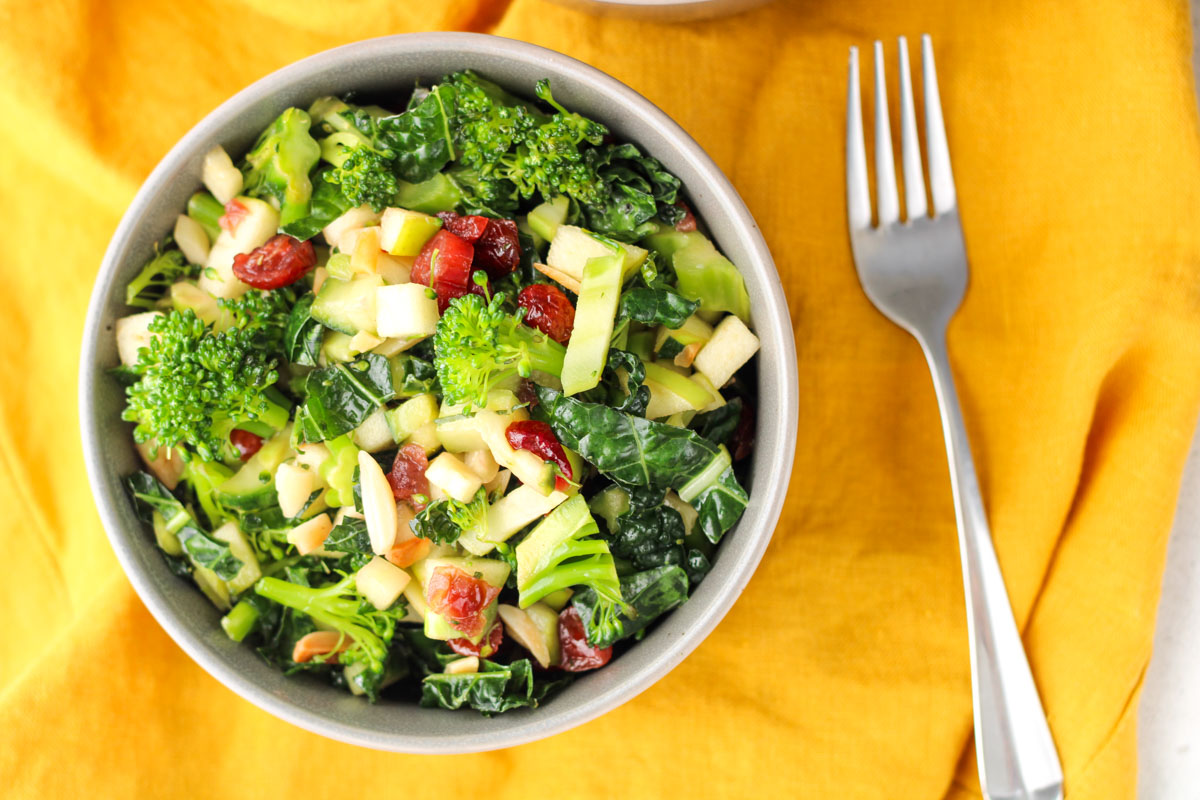 A small bowl of Kale and Broccoli Salad on a orange table cloth.