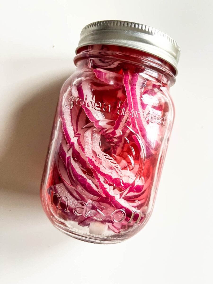 Jar of red onions in pickling liquid.